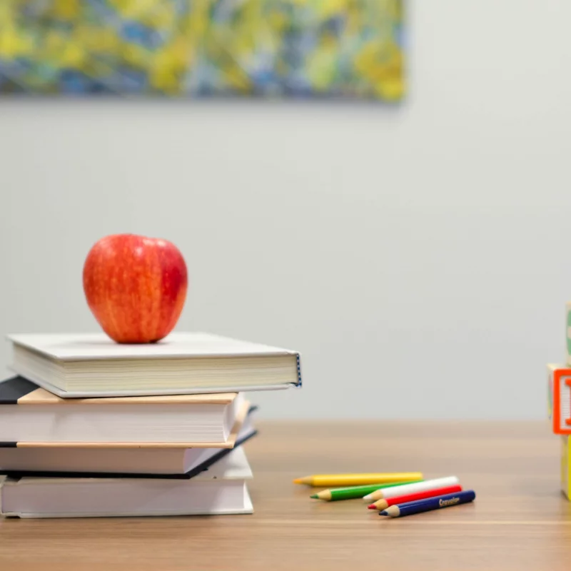 Bücherstapel auf Schreibtisch mit Stiften neben dran